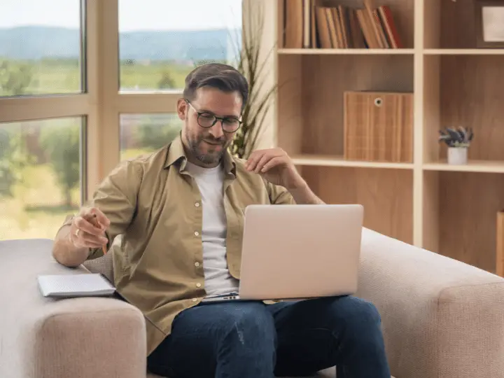 Man participating in telehealth mental health counseling session on laptop at home